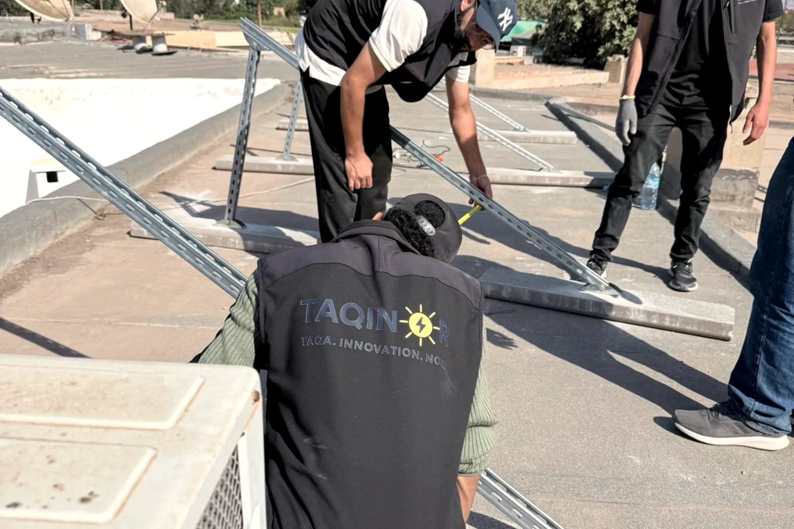 Trois installateurs Taqinor mesurent l'implantation des rails sur le toit, Nouaceur