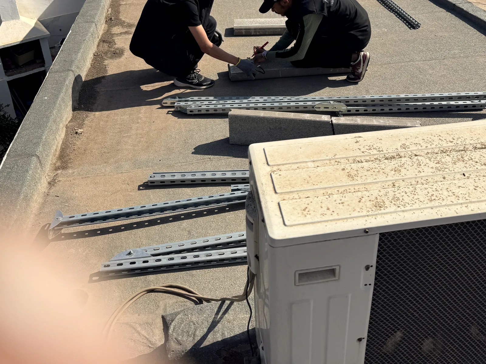 Deux installateurs Taqinor posent les blocs de lestage et les rails avant la pose des panneaux, Nouaceur
